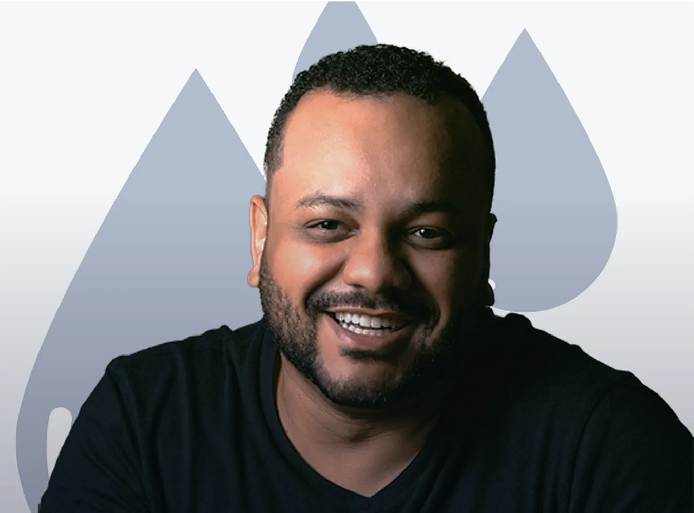 A bearded man in a black T-shirt laughs toward the camera beside the brand's blue droplet shapes