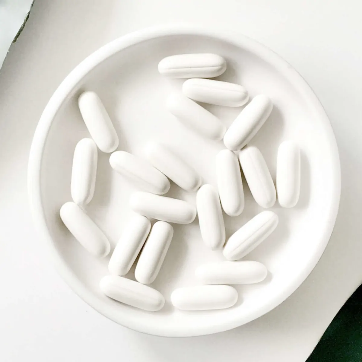 Close-up of white capsules in a small white dish